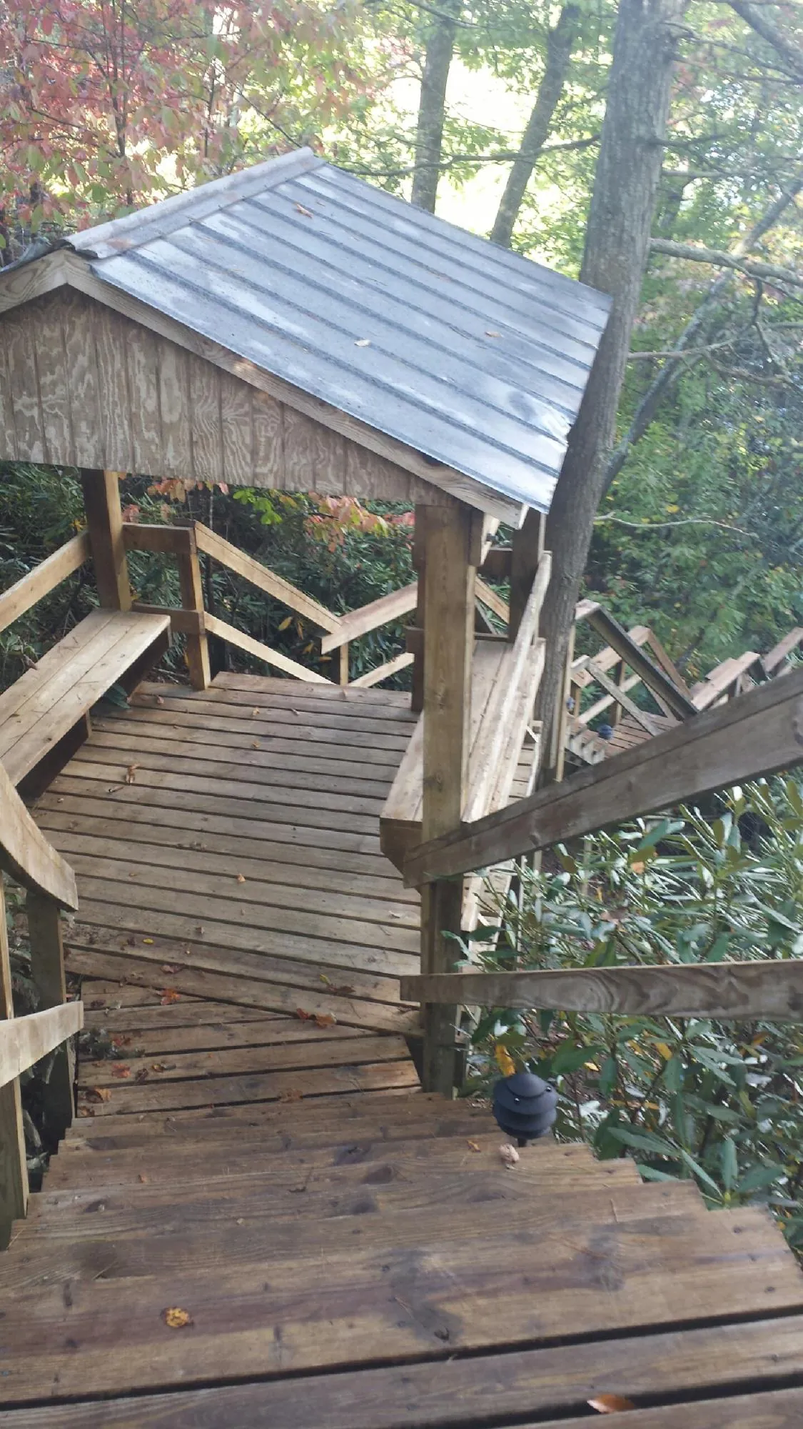 Metal roofed shelter over wooden steps on a wooded walkway — Skylight Repair & Installation work by our crew in Dumont